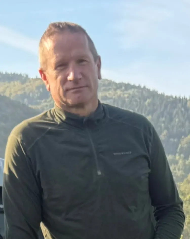 Stanisław Wąsik na winnicy, na tle zalesionych wzgórz